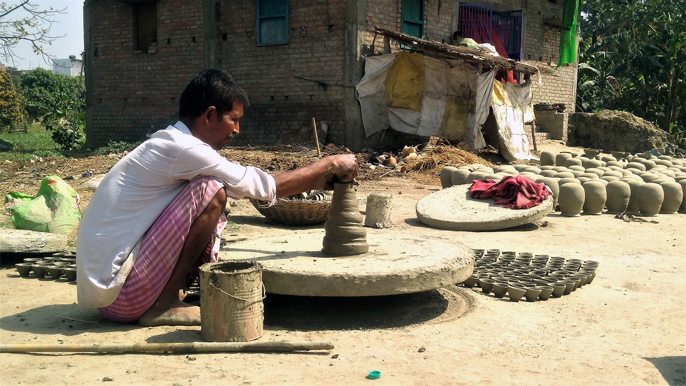 Sudama shaping clay to make pots