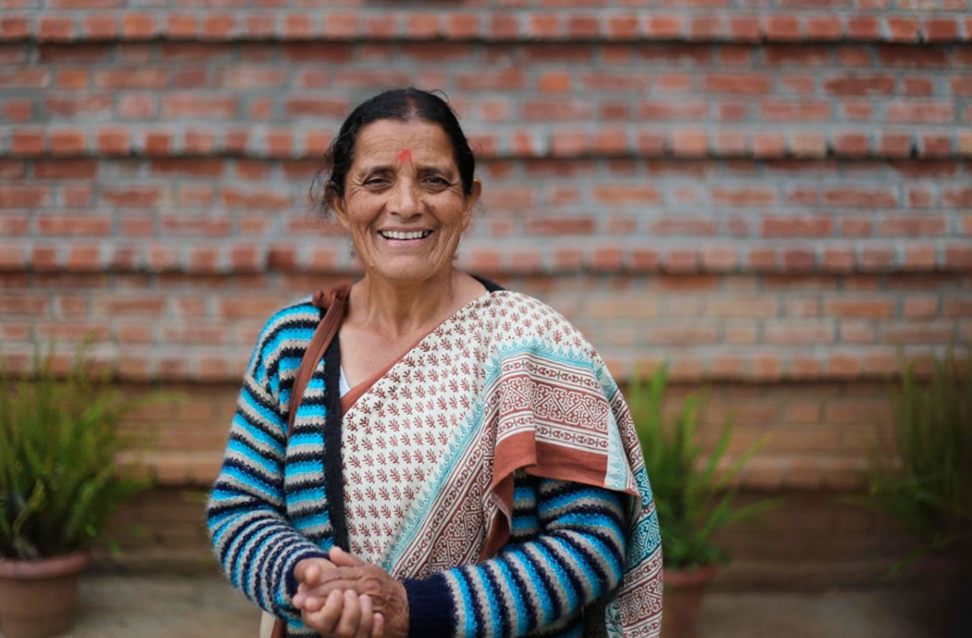 Basanti Samant standing in front of a red brick wall