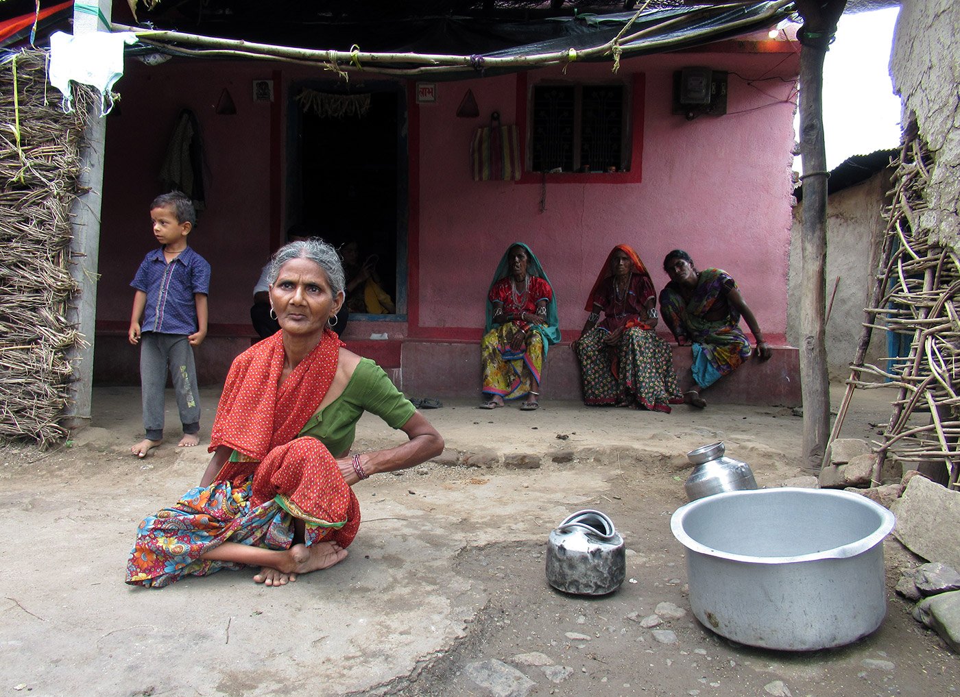 Woman sitting in front of home with three people and a child in the background