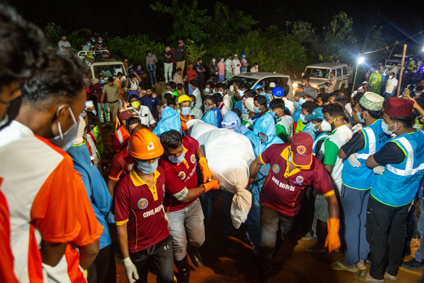 The bodies of people who died are wrapped in white and carried