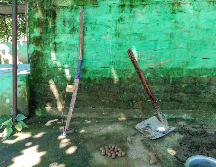 A pile of rodas (pellets) made from wet clay and a kaman (bow) are the tools of the caretaker's trade.