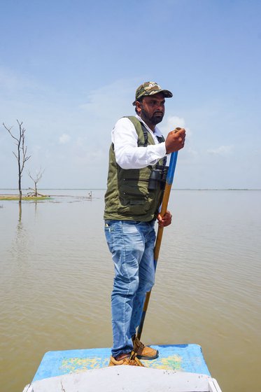 Gani on a boat with his camera equipment, looking for birds to photograph on the Nal Sarovar lake in Gujarat