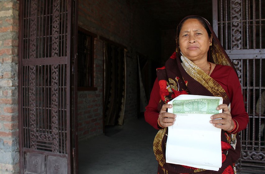 Kamla Devi in front of her home in the village of Pindari (Udham Singh Nagar), Uttarakhand. She holds a blank stamp paper signed by her husband Harish Chandra