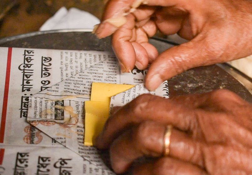 Chobi Saha getting ready to make paper bags. ‘First, I use a knife to divide a paper into three parts. That makes six pieces. Then I apply glue in circles. After that I fold the paper into a square and apply glue to the other side. This is how I make the packets,’ she says as she works