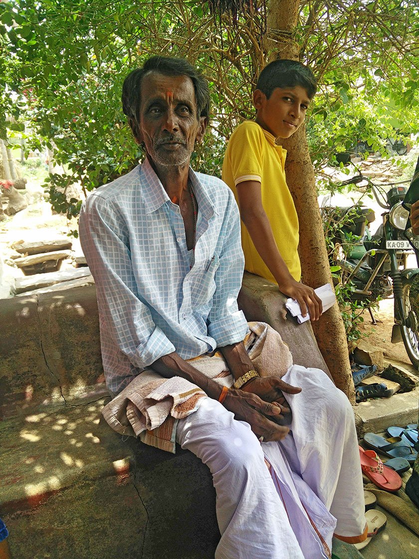 An old man and a young boy under the shade of a tree