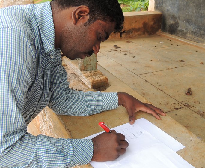 A man sitting and writing on a piece of paper