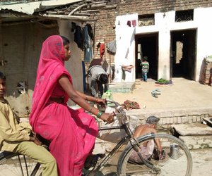 Women riding cycle with son riding pillion 