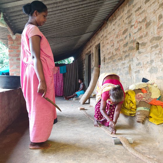 Elisaba (standing on the left) and Jolen measure the strips into equal lengths before they are cut. A wooden stick (right) comes in handy to ensure correct measurements