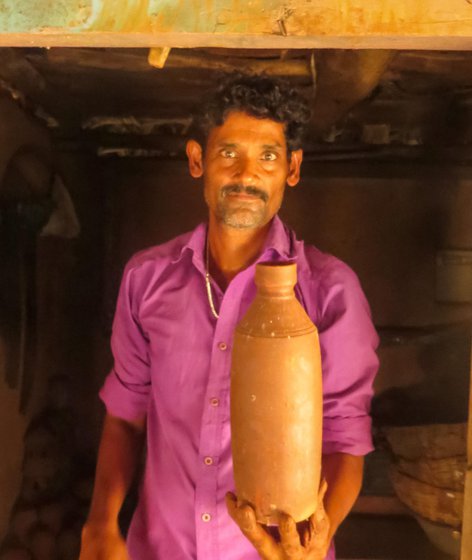 Right: He holds up a clay bottle he recently finished baking