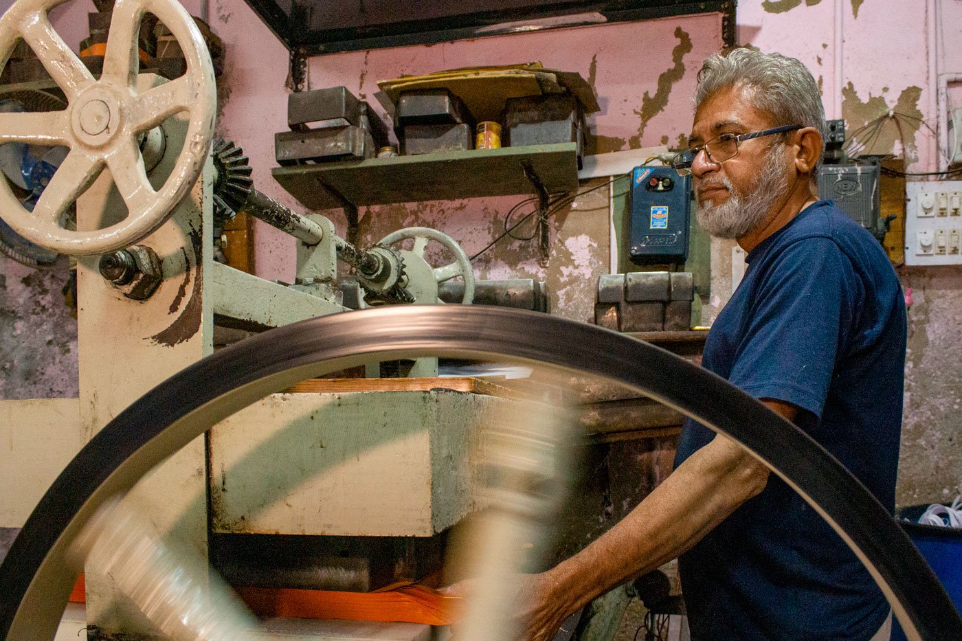 Maqbul Ahmad Jamaluddin Shaikh a worker at Om Traders operating the punching machine that cuts sheets of paper to a size and shape of ready for folding. Most workshop owners handle the cutting and punching machines themselves