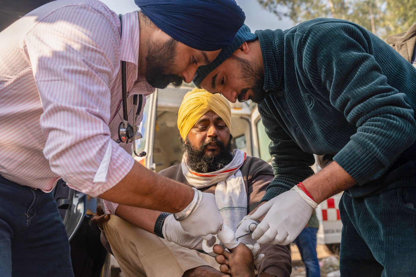 Dr. Mandeep Singh (pink shirt) tends to his patients in his camp at Shambhu Border. He runs the Baba Shree Chand Ji hospital back in his village, Hoshiarpur