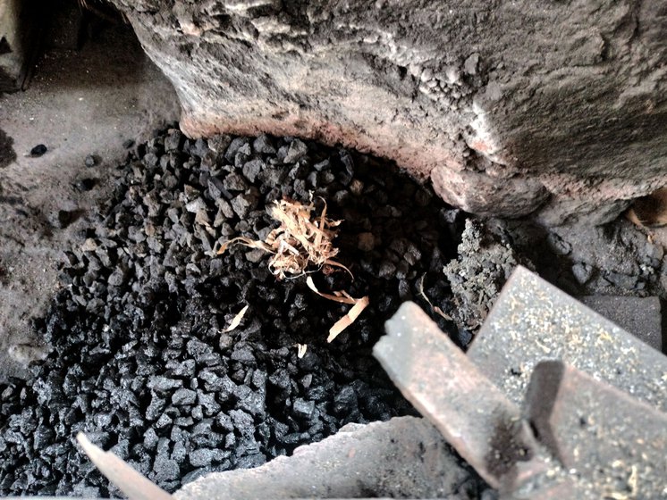 He adds small strands of wood shavings (right) to ignite the forge