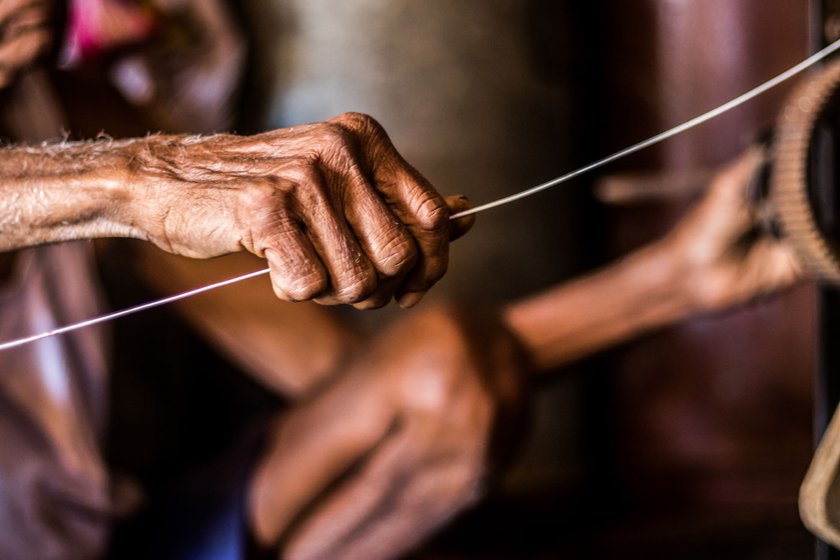 The 82-year-old's hands at work, holding a wire while rewinding a motor