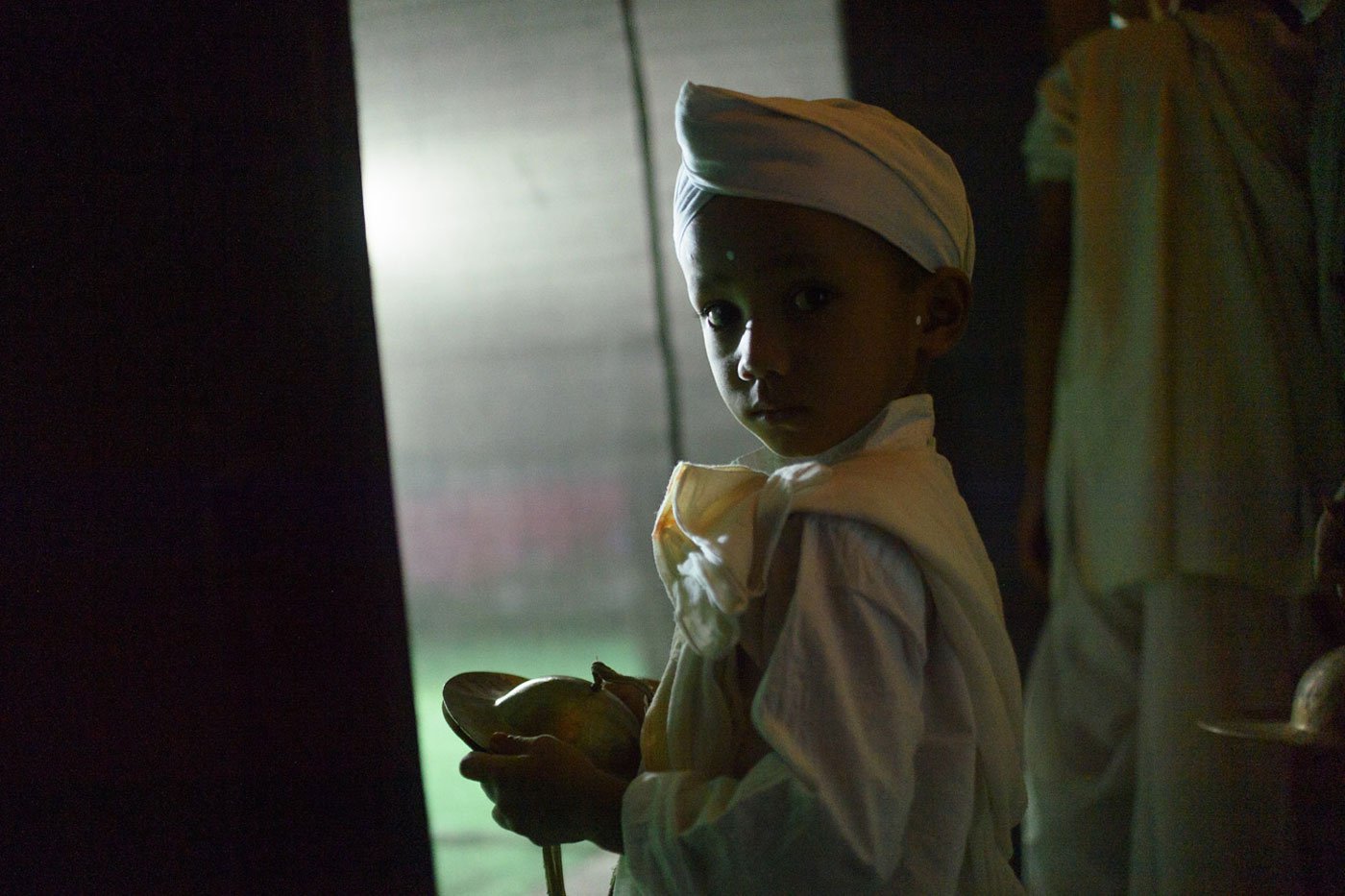 Anurag Saikia, one of the youngest in the group, waits near the wings of the stage. The children in the satra start their lessons early