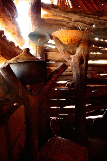 A kitchen in a Bhil home. The utensils are kept on stands made of logs, away from dogs and cats