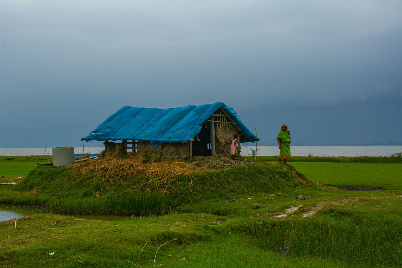 Purnima Mondal, 46, of Kakdwip island, Kakdwip block, South 24 Parganas standing in front of her thatched house with one of her children. Her husband, Provas Mondal, 52, is a construction worker in Nashik, Maharashtra. She catches fish and crabs from nearby rivers everyday. 

