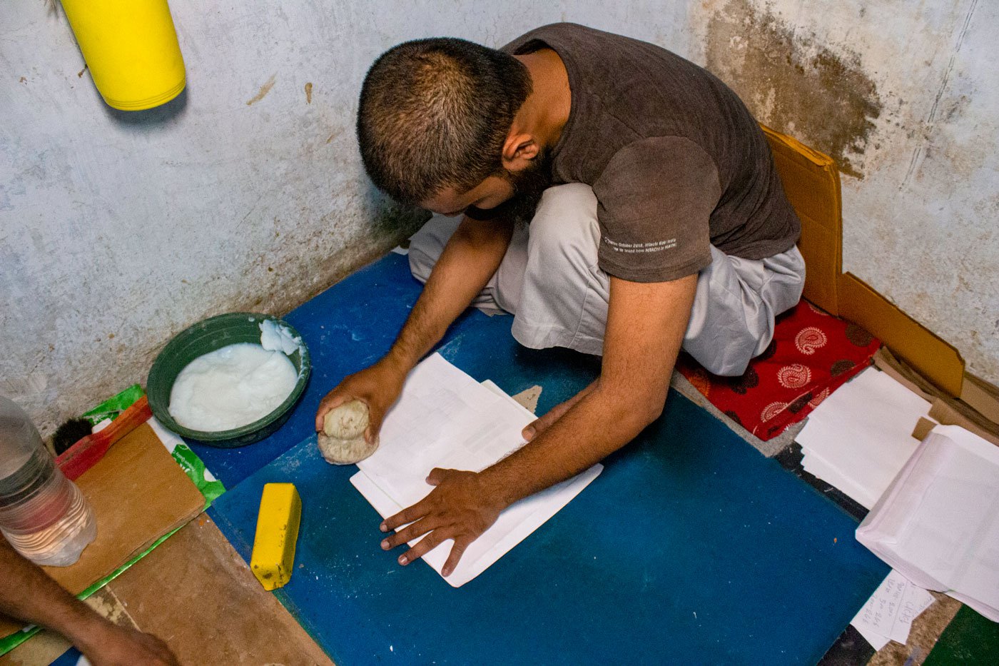 Sameeruddin Shaikh applying paste to dhapa , the right flap of the envelope paper. He works on 100 envelopes at a time