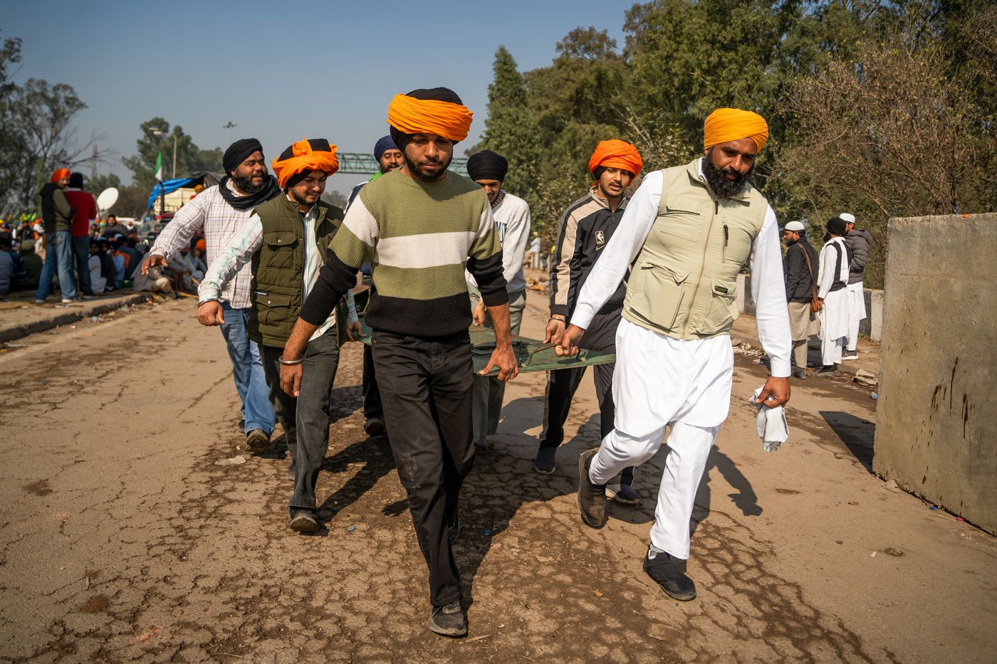 Farmers carry a barricade to set it up and use it as a shield against the rubber bullets