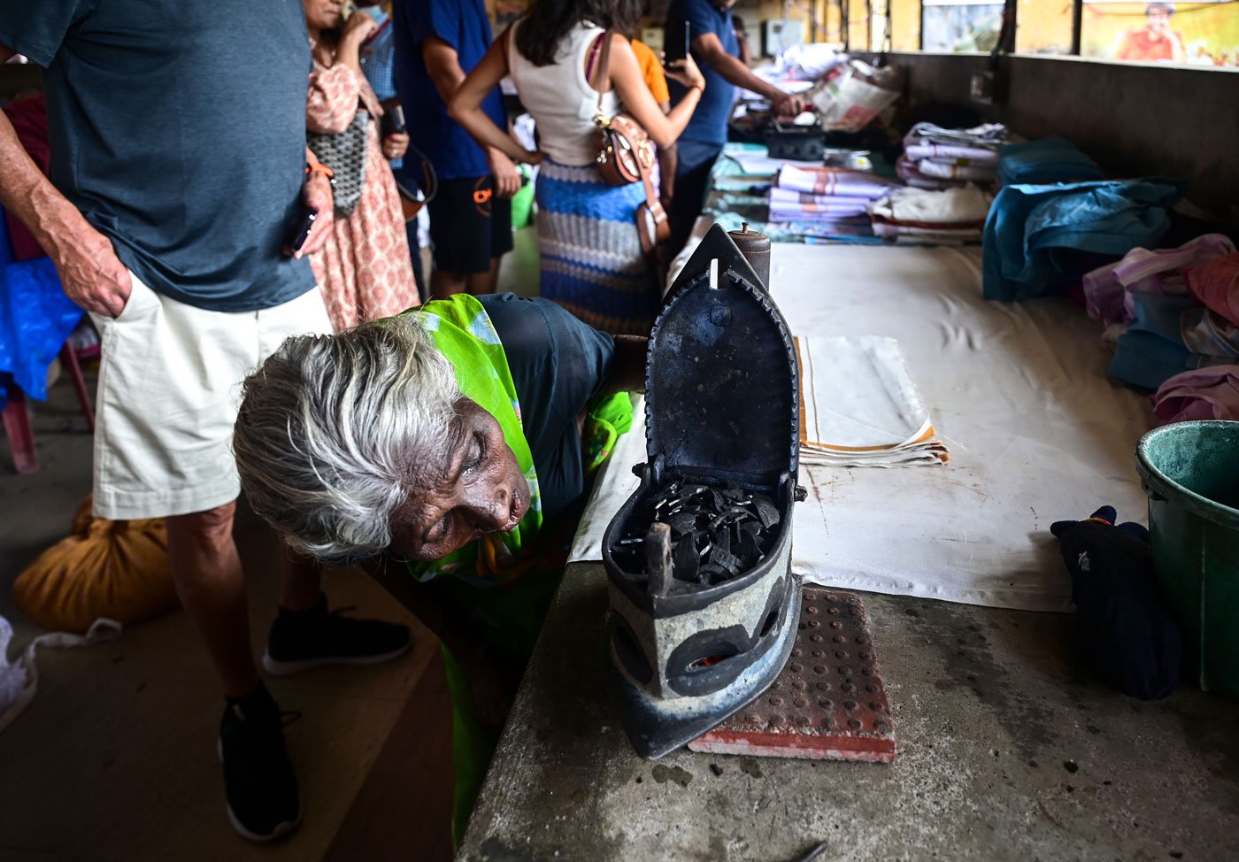 Sarojini, 80, blowing on a traditional box iron filled with hot coal