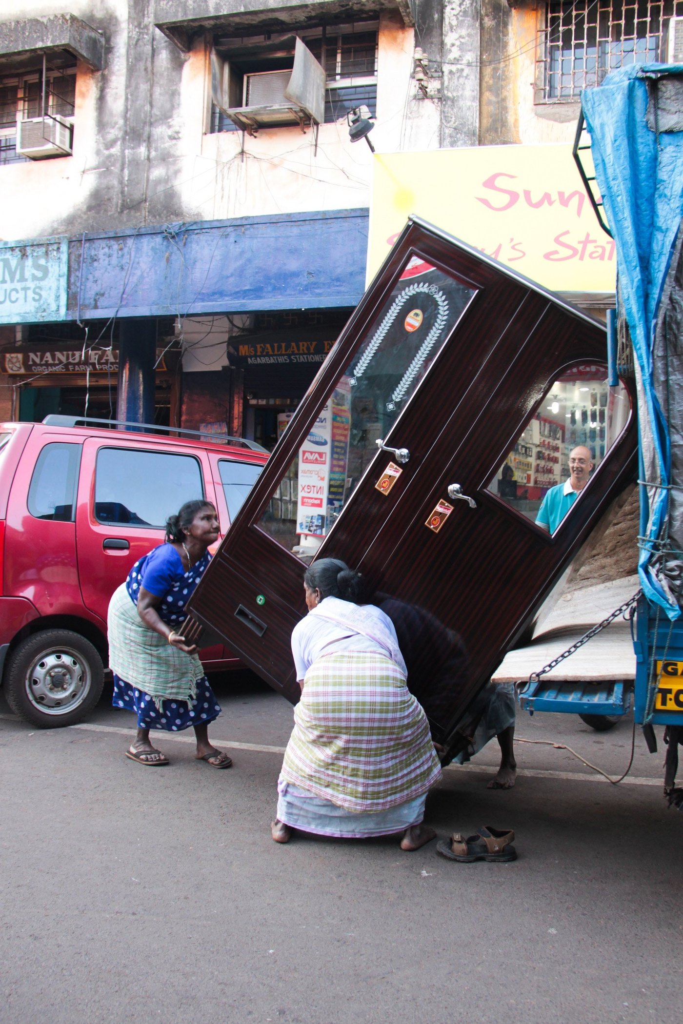 Two women trying to lift almirah