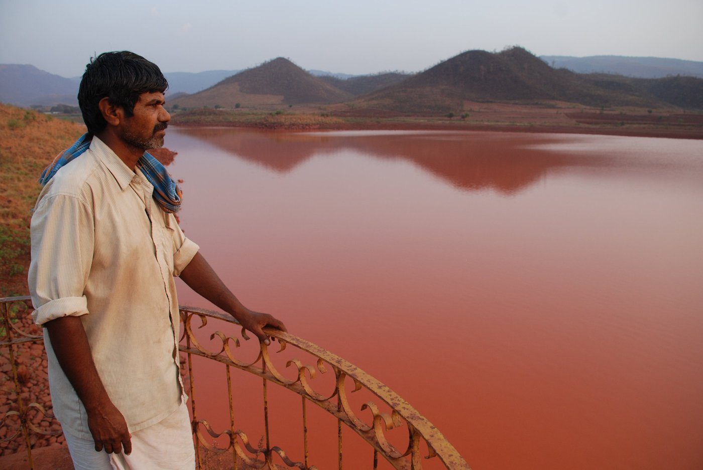 Man looking out to polluted reservoir 